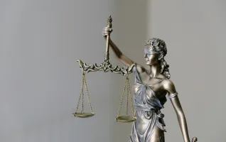 Statue einer Frau mit verbundenen Augen welche in einem Kleid eine Waage hält