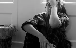 Foto eines Schülers, der auf dem Boden sitzt und gegen Depressionen ankämpft