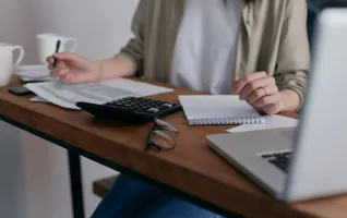 Frau macht sich Notizen, während sie einen Laptop benutzt