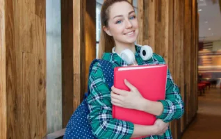 Student mit Büchern steht im Universitätsflur