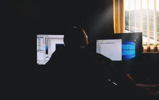 Mann analysiert Daten auf Monitoren für Wirtschaftsinformatik
