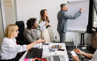 Ein Mitarbeiter präsentiert seinen Kollegen während eines BWL-Meetings