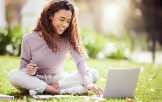 Studentin sitzt in der Natur vor einem Laptop in der richtigen Lernumgebung