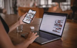 Social-Media-Manager nutzt Smartphone und Laptop