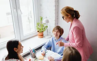 Eine Frau, die in einem hellen, kooperativen Klassenzimmer mit Kindern arbeitet