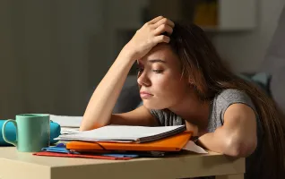 Studentin sitzt verzweifelt an ihren Unterlagen und fühlt sich gestresst