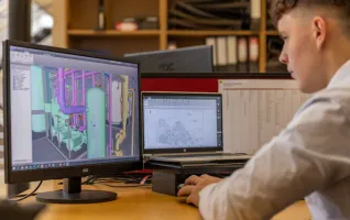 Industrieingenieur, der in einer Büroumgebung mit CAD-Software auf zwei Monitoren arbeitet