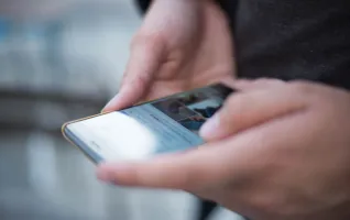 Close-up of hands using a smartphone with a touchscreen, emphasizing mobile technology.