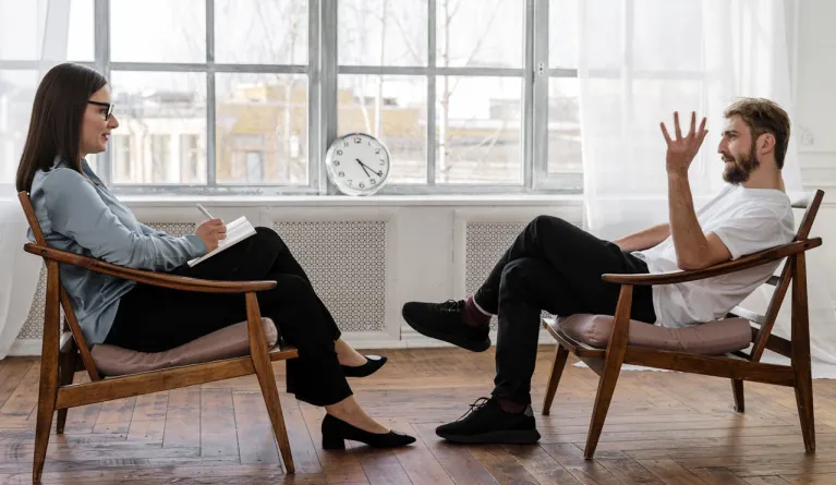 two-people-sitting-on-wooden-chairs-opposite-each-other