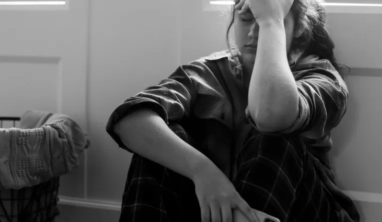 Foto eines Schülers, der auf dem Boden sitzt und gegen Depressionen ankämpft