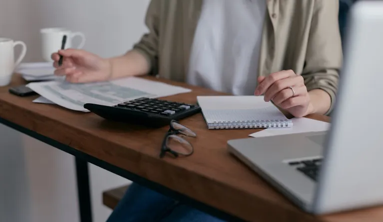 Frau macht sich Notizen, während sie einen Laptop benutzt