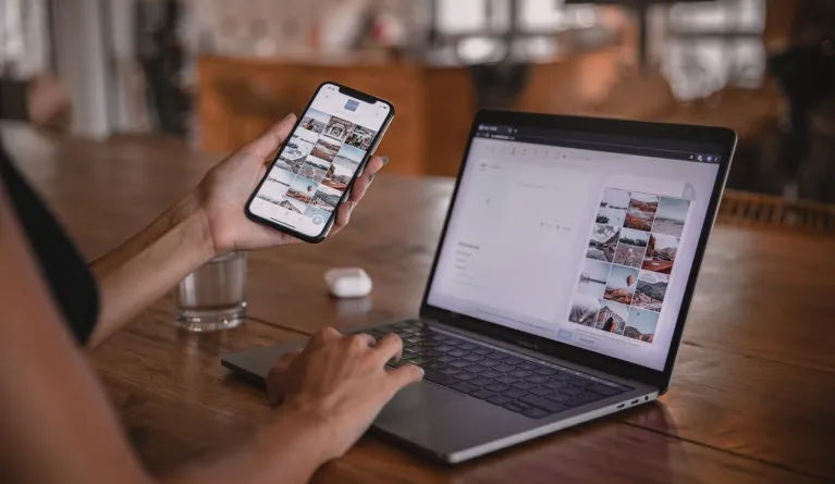 Social-Media-Manager nutzt Smartphone und Laptop