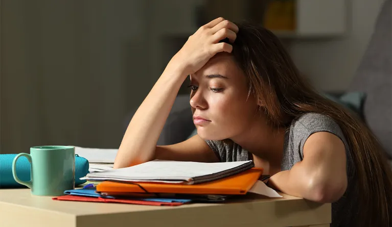 Studentin sitzt verzweifelt an ihren Unterlagen und fühlt sich gestresst, durch den TikTok Trend "Toxic Study Motivation"