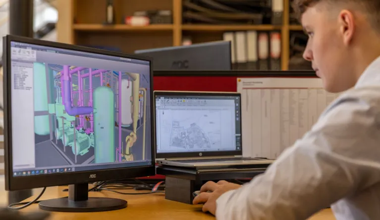 Industrieingenieur, der in einer Büroumgebung mit CAD-Software auf zwei Monitoren arbeitet